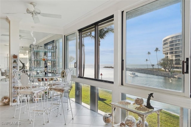 sunroom / solarium featuring a water view and ceiling fan