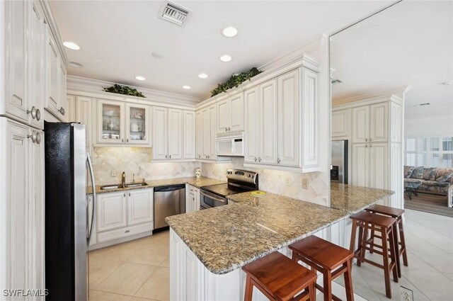 kitchen featuring kitchen peninsula, a kitchen breakfast bar, stainless steel appliances, sink, and white cabinets