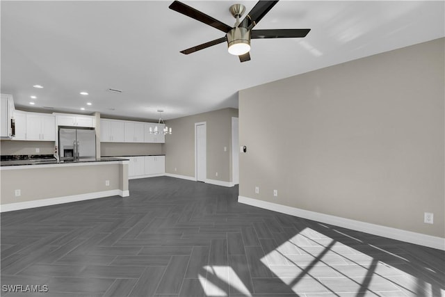 unfurnished living room featuring dark parquet floors and ceiling fan with notable chandelier