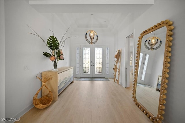 entryway featuring ornamental molding, french doors, light hardwood / wood-style floors, and a chandelier