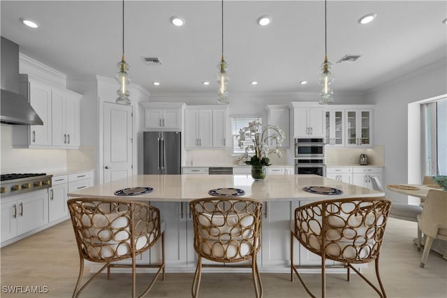 kitchen with a spacious island, a breakfast bar, pendant lighting, and appliances with stainless steel finishes