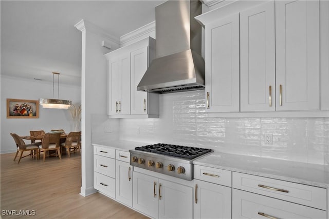 kitchen with light stone countertops, ventilation hood, stainless steel gas stovetop, white cabinets, and tasteful backsplash