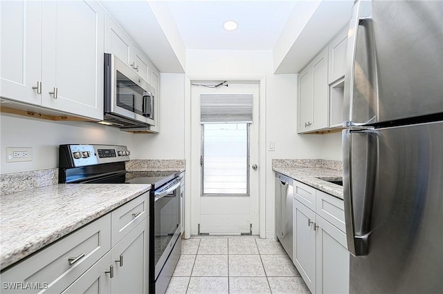 kitchen featuring appliances with stainless steel finishes, light tile patterned floors, and white cabinetry