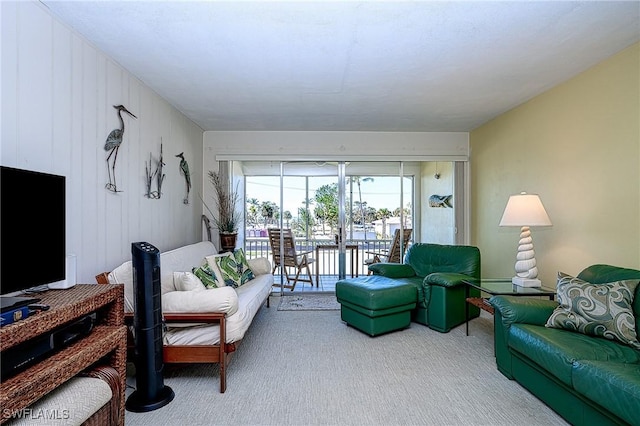 carpeted living room with wooden walls and a water view