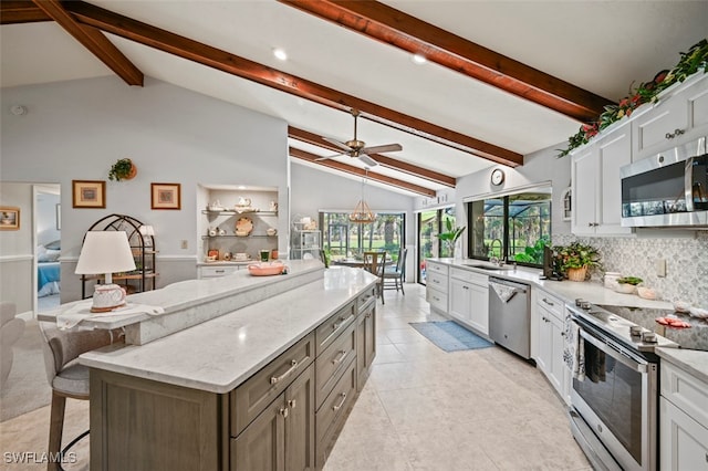 kitchen with backsplash, sink, vaulted ceiling with beams, appliances with stainless steel finishes, and white cabinetry