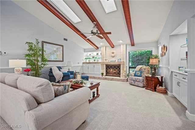 carpeted living room with lofted ceiling with skylight, a large fireplace, and ceiling fan