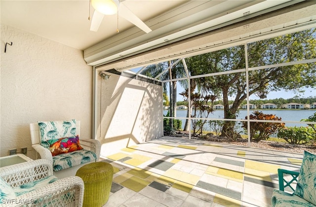 sunroom with ceiling fan and a water view