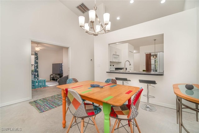 dining space featuring a high ceiling, ceiling fan with notable chandelier, and sink