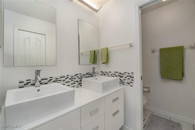 bathroom with tile patterned floors, vanity, toilet, and tasteful backsplash