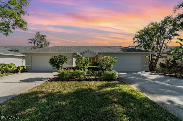 single story home featuring a garage and a lawn