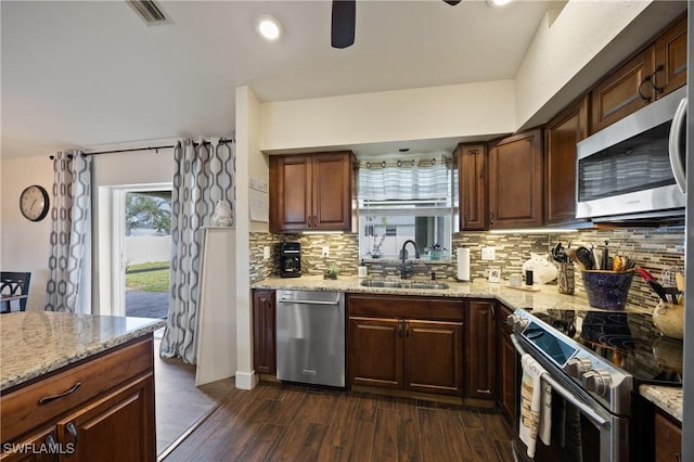 kitchen featuring decorative backsplash, sink, dark wood-type flooring, light stone countertops, and appliances with stainless steel finishes