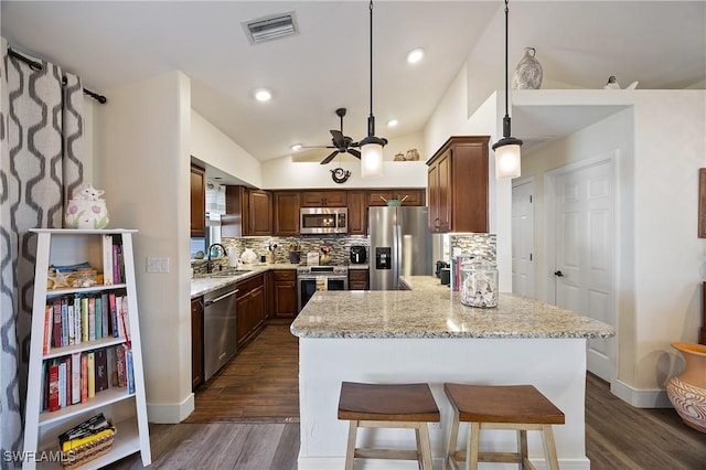 kitchen with stainless steel appliances, decorative backsplash, dark hardwood / wood-style flooring, and light stone countertops