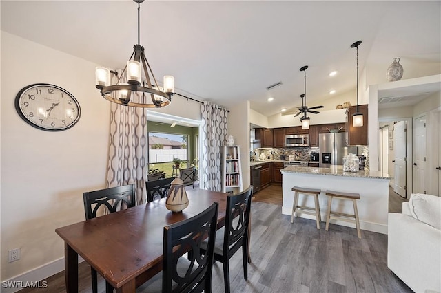 dining room with dark hardwood / wood-style flooring, lofted ceiling, and ceiling fan with notable chandelier