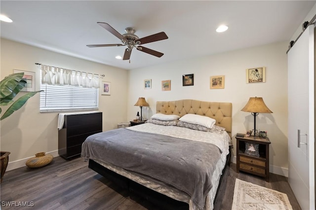 bedroom featuring ceiling fan, a barn door, and dark hardwood / wood-style floors