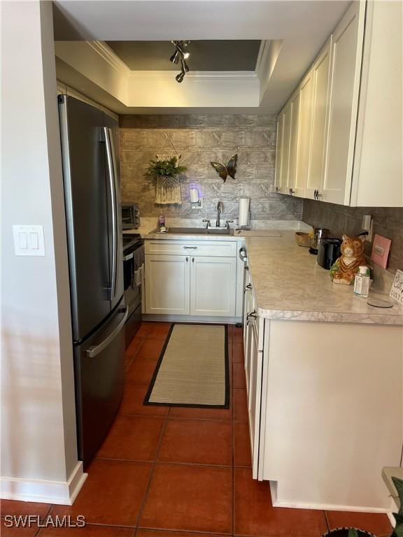 kitchen featuring electric range, white cabinetry, light countertops, freestanding refrigerator, and tasteful backsplash