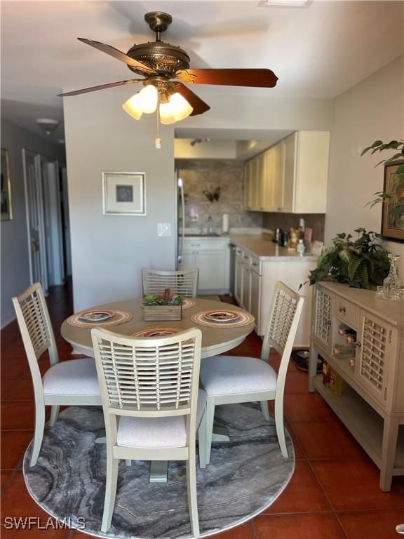 dining space featuring ceiling fan and dark tile patterned floors