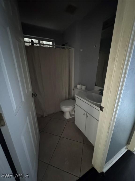 bathroom with a shower with curtain, vanity, tile patterned floors, and toilet