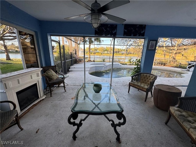 sunroom featuring a water view and ceiling fan