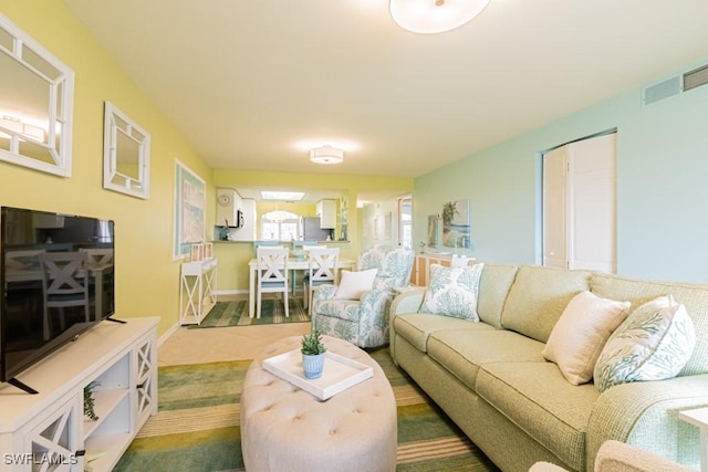 living area with baseboards and visible vents