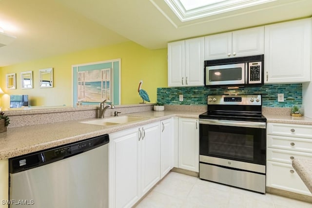 kitchen featuring sink, light tile patterned floors, appliances with stainless steel finishes, backsplash, and white cabinets