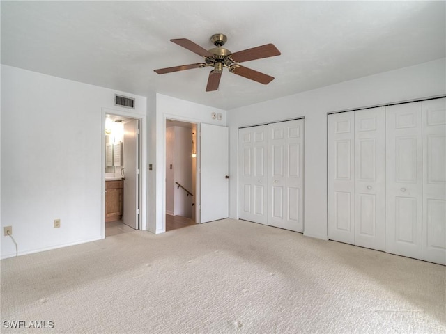 unfurnished bedroom featuring light carpet, two closets, ceiling fan, and ensuite bathroom