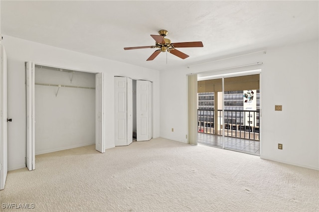 unfurnished bedroom featuring access to exterior, light colored carpet, multiple closets, and ceiling fan