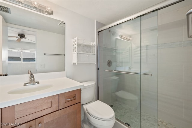 bathroom with a shower with door, vanity, ceiling fan, and toilet