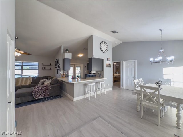 interior space with ceiling fan with notable chandelier, light hardwood / wood-style floors, sink, and vaulted ceiling