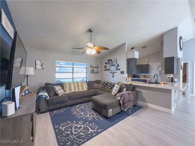 living room featuring ceiling fan, lofted ceiling, sink, and light hardwood / wood-style flooring