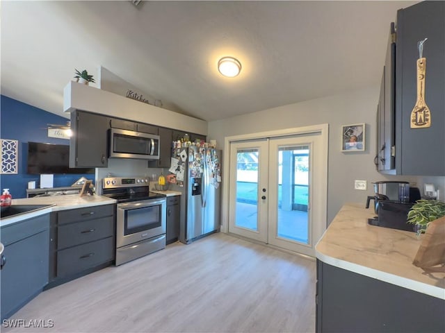 kitchen featuring lofted ceiling, french doors, sink, light hardwood / wood-style flooring, and stainless steel appliances