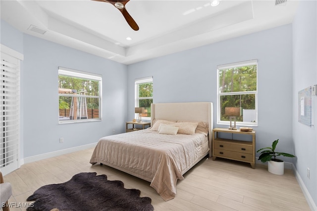 bedroom featuring a raised ceiling, ceiling fan, and light hardwood / wood-style flooring