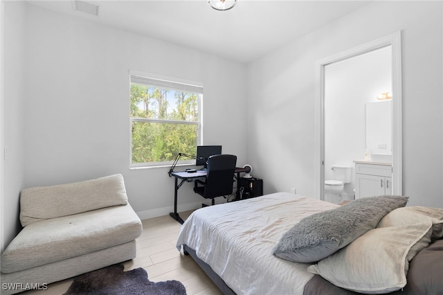 bedroom with ensuite bathroom and light hardwood / wood-style floors