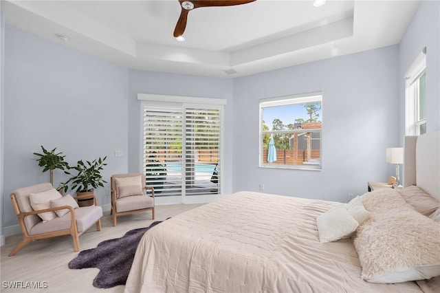 bedroom with access to outside, a tray ceiling, and ceiling fan