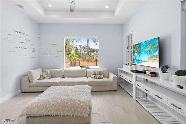 living room with light hardwood / wood-style floors and a tray ceiling