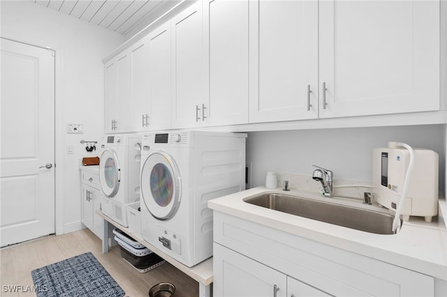 washroom with cabinets, independent washer and dryer, sink, and light hardwood / wood-style flooring