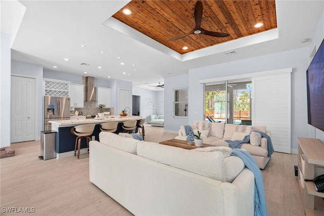 living room featuring light wood-type flooring, wooden ceiling, and a tray ceiling