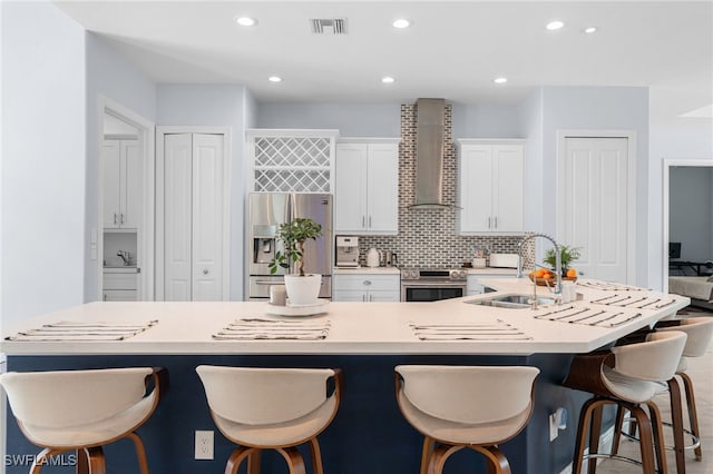 kitchen featuring a large island with sink, sink, wall chimney exhaust hood, and stainless steel appliances