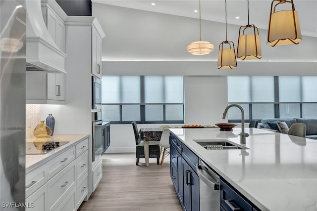 kitchen featuring custom range hood, white cabinets, hanging light fixtures, and sink