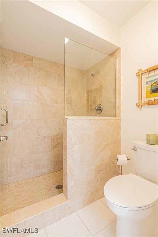 bathroom featuring a tile shower, tile patterned floors, and toilet