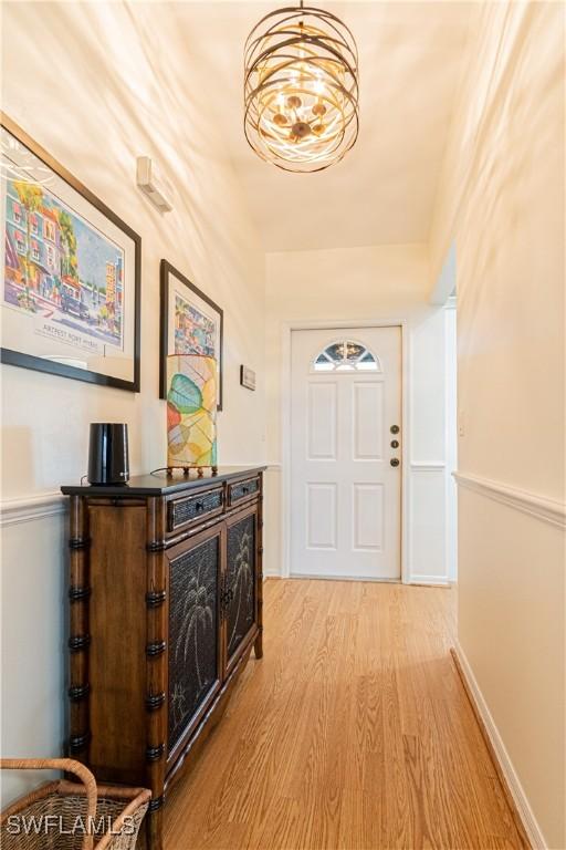 doorway with a chandelier and light wood-type flooring