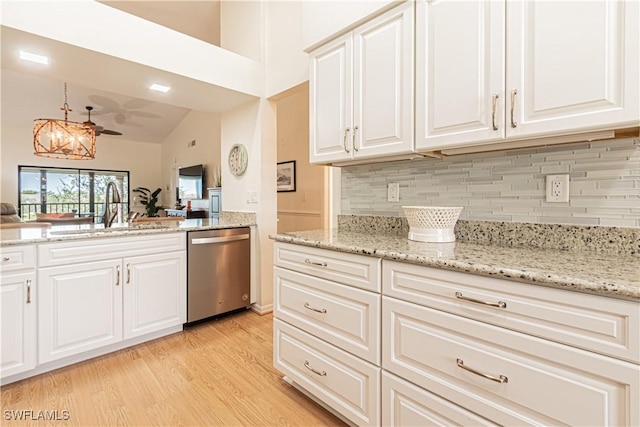 kitchen featuring sink, dishwasher, light stone counters, white cabinets, and light wood-type flooring