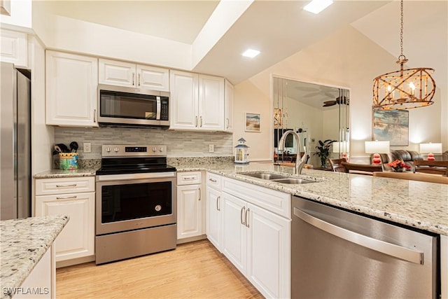 kitchen featuring vaulted ceiling, appliances with stainless steel finishes, sink, and white cabinets