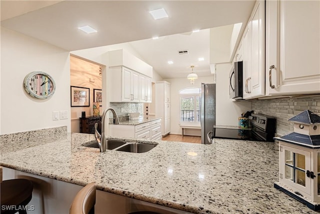 kitchen with sink, stainless steel appliances, kitchen peninsula, and a kitchen bar