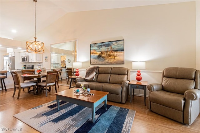 living room featuring high vaulted ceiling and light hardwood / wood-style flooring