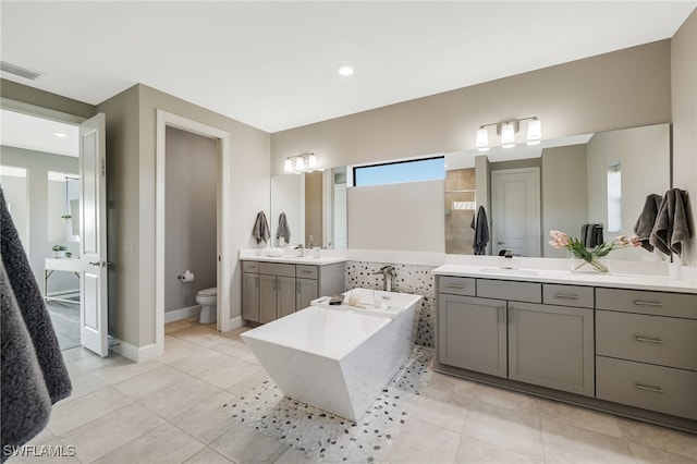 bathroom featuring tile patterned floors, vanity, toilet, and a washtub