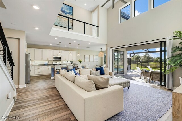 living room featuring a towering ceiling and light wood-type flooring