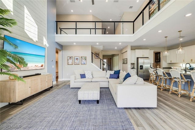 living room with sink, a high ceiling, and light wood-type flooring