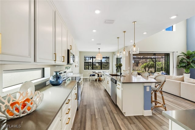 kitchen featuring a kitchen breakfast bar, white cabinetry, hanging light fixtures, and appliances with stainless steel finishes