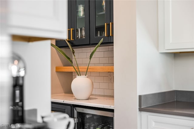 room details with tasteful backsplash, wine cooler, and white cabinetry