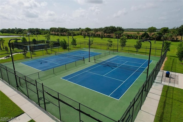 view of sport court with a lawn and fence